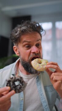 A man eating two donuts simultaneously with delight. Sugar addiction