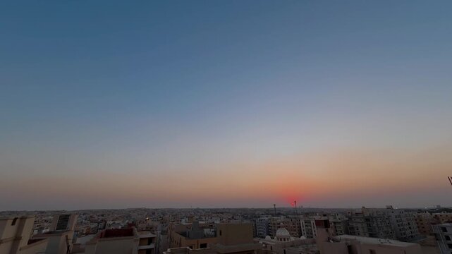Time-lapse of a beautiful golden sunset over a dense urban city skyline, featuring multiple airplanes leaving white contrails as they fly across the clear twilight sky.