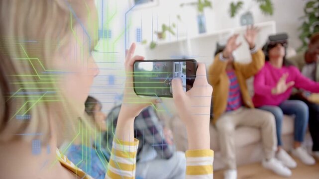 Teen holding phone tapping screen, filming group on sofa, VR sets reaching, tech overlay clearing