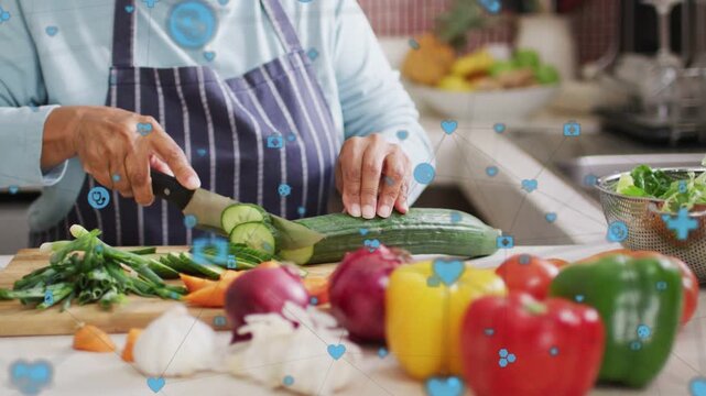 Hand grasping knife, home cook slicing cucumber on board, blue icons drifting over hands for salad