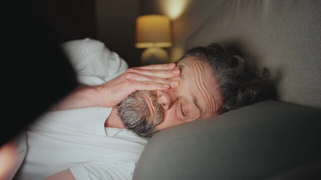 A man lying in bed using smartphone late at night. 