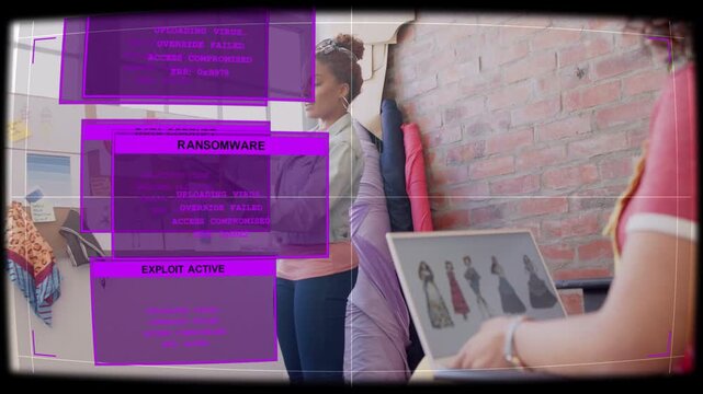 Standing woman pointing fashion board as purple ransomware overlay rising colleague fixing laptop