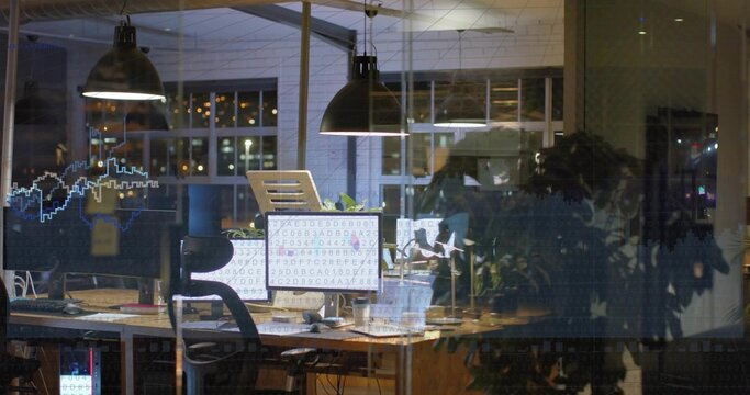 Displaying workstation with dual monitors showing code at nighttime office, with laptop and plant