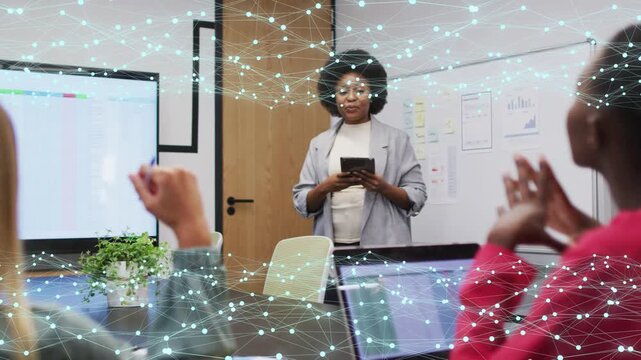 Female lead checking tablet, gesturing to display, running business update with colleagues clapping