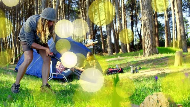 Beanie-wearing camper shoveling after group plan, clearing rock ring for camping, bokeh veils scene