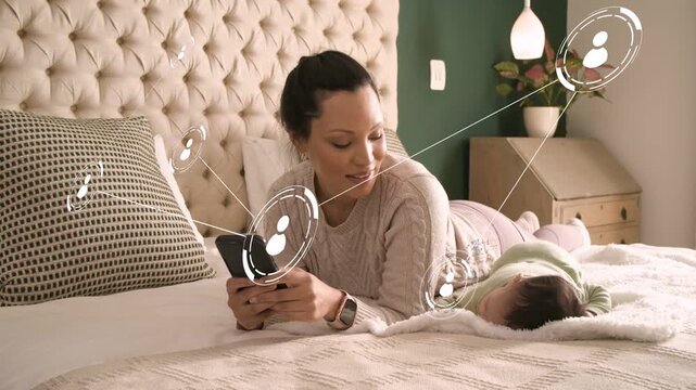 Mother on bed tapping smartphone and generating technology avatar network while monitoring infant