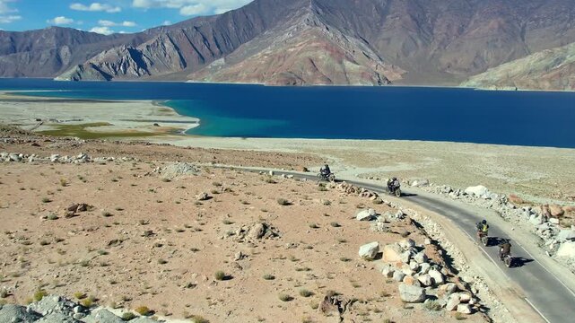 Touring motorbikes Follow Scenic Shoreline Routes Along Pristine Mountain Lake With Rugged Terrain