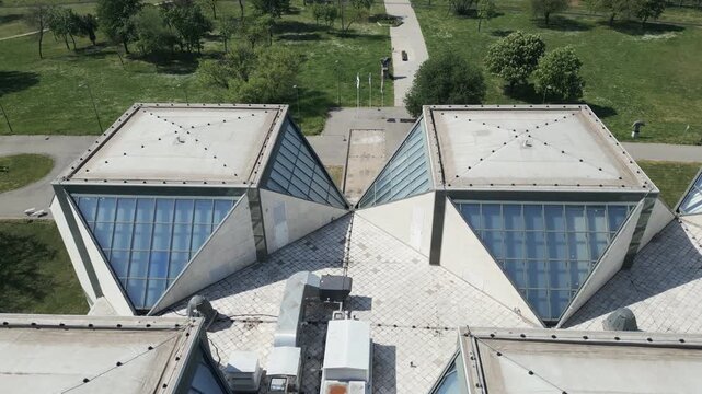 Slow drone flight over sharp triangular roof, Brutalist architecture, New Belgrade, Serbia.