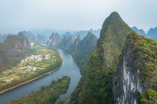Lush karst peaks rise steeply from calm river waters. China.