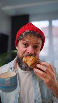 A man enjoying a fresh croissant and coffee for breakfast. Slow motion