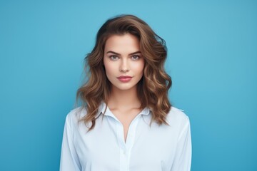 Obraz premium Young professional woman with wavy hair posing confidently against a solid blue background
