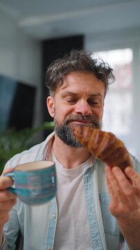 A man enjoying a fresh croissant and coffee for breakfast