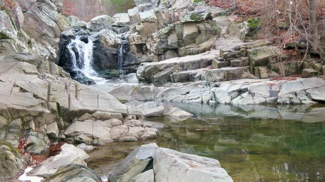 View of a waterfall cascading over jagged rocks into a clear pool at Scott's Run Nature Preserve in McLean, Virginia, United States.