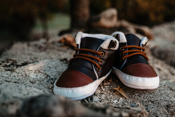 Brown Leather Baby Boots with Fleece Lining on Rocky Outdoor Surface © Anghelq