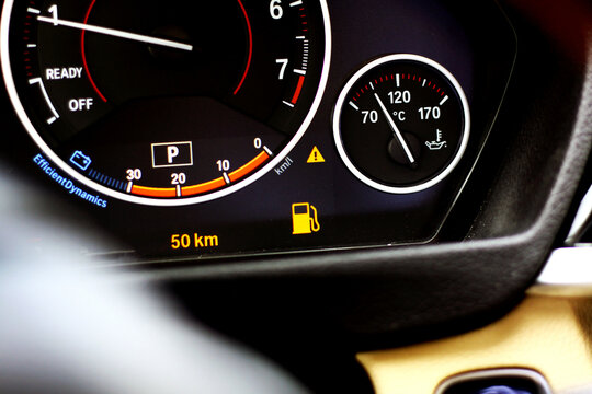 Car dashboard close up with low fuel warning light, empty tank indicator 