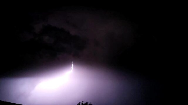 Lightning storm in the night sky bolt of electricity striking through dark atmospheric clouds during a storm slow motion 240fps footage