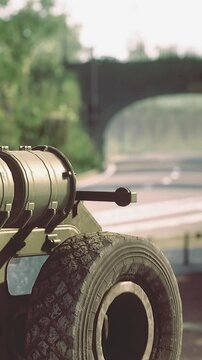 A military vehicle shows a mounted weapon positioned on the side facing a city road. The scene takes place during daytime with clear sight of the surroundings.