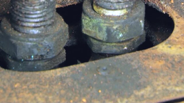 Steadfast view captures robust metal bolts and nuts securing vital air filter component. Weathered surfaces reveal enduring grit of machinery, hinting at essential maintenance or diligent repair work.