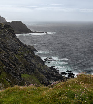 Rugged, rocky coastline of Scotland's Island of Islay faces the ever crashing waves of the Northern Atlantic Ocean on a grey day.