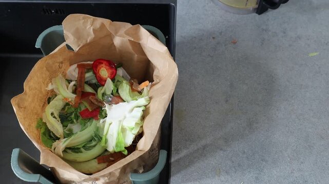 Stockholm, Sweden A cook in a residential kitchen cleans up vegetable cuttings into a compostable brown paper bag. 
