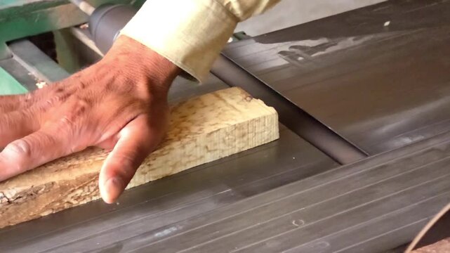 Carpenter processing a raw wooden plank through an industrial surface planer machine in a professional workshop High Quality Footage