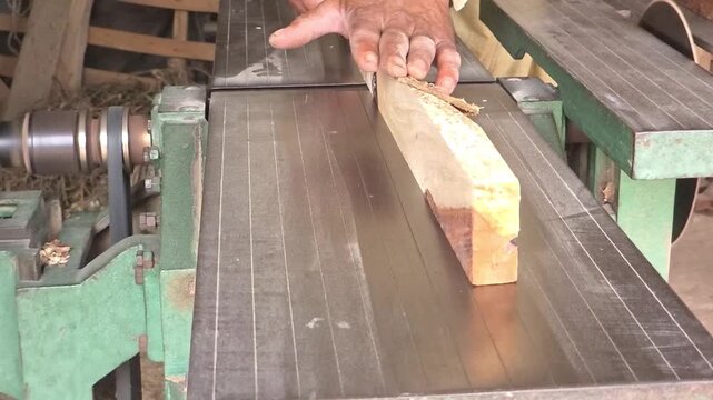 Woodworker smoothing a raw timber plank using a professional jointer machine in a bright carpentry workshop High Quality Footage