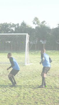 Vertical video: Soccer duo running to goal eyeing ball defending as streaks overlaying players