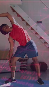 Vertical video: Man starting stretch by raising right arm doing side-bend on blue mat for fitness