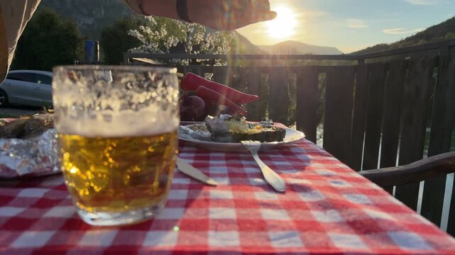 Close-up of adding seasoning to food during an outdoor picnic dinner on a terrace with scenic mountain view. Warm sunset light, lens flare, and rustic countryside atmosphere. Concept of cooking, outdo