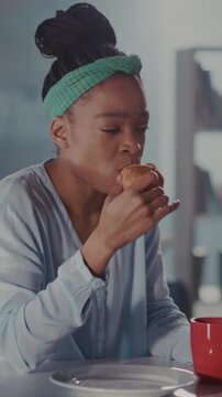 Woman sampling flaky croissant happily, Woman with green headband enjoys flaky pastry in her warm home kitchen