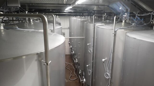 Brewery fermentation tanks in a production facility with visible piping and equipment showcasing the brewing process