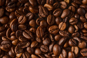 Obraz premium Roasted coffee beans texture background. Full frame closeup of aromatic arabica grains. Top view pattern of brown caffeine ingredient. Fresh energy drink wallpaper