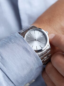 Blank wristwatch worn over shirt cuff, hand adjusting bezel detail, luxury close-up product feel, sharp focus