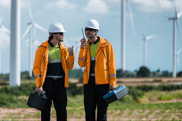 Obraz premium Professional Technicians Discussing Renewable Power Operation, Talking Walking Wind Turbine Background. Reporting Wind Turbine Status. Future Grid Development Team Discussing Field Inspection