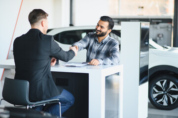 Client and salesman shaking hands sealing car deal at dealership © Serhii
