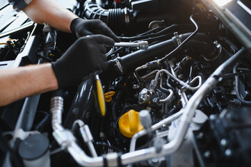 Fototapeta premium Mechanic servicing car engine using professional tools