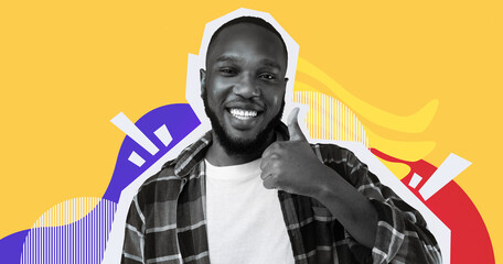 A cheerful African American man is smiling and giving a thumbs up. He stands against a bright yellow background in a studio. This pose shows joy and approval, creating a lively atmosphere. © Prostock-studio