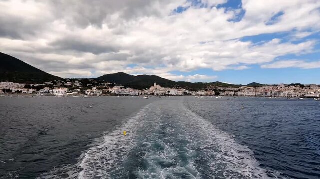 A classic view of Cadaqu&eacute;s receding into the distance as you sail through the bay, leaving a trail of foam in your wake. Cadaqu&eacute;s is a municipality in the province of Girona, Catalonia, Spain.