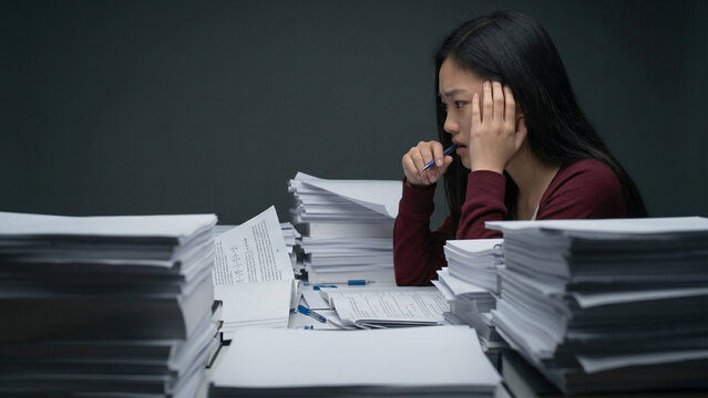 積み重なった書類に囲まれている女性