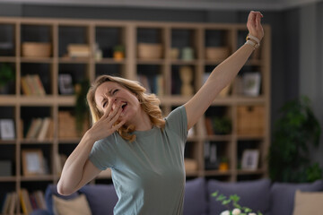 Fototapeta premium Woman yawning and stretching in living room after waking up
