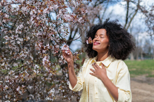 Young African woman enjoying flowers blooming in the forest