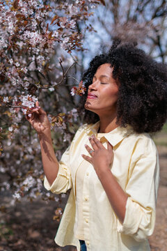 African woman enjoying flowers blooming in the forest