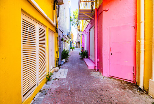 Narrow colorful alleyway with bright pink and yellow buildings on a sunny day in Willemstad Curacao
