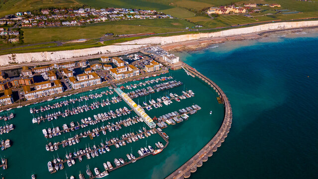 Modern yacht marina nestled beneath dramatic white chalk cliffs at sunset
