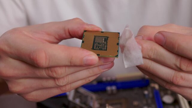 Carefully cleaning processor surface prior to thermal paste application process. Meticulous hand movements as thermal paste is gently wiped off processor surface for cleaning