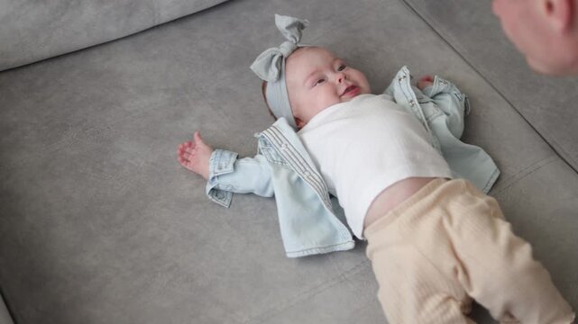 Adorable baby girl giggling while playing with her father on a sofa