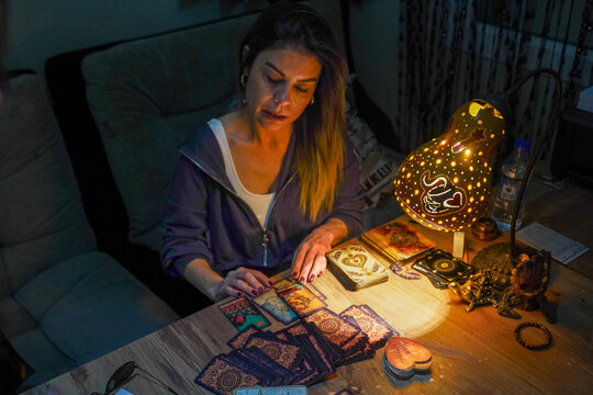 Woman fortune teller reading tarot cards with mystical gourd lamp at night