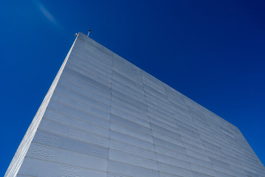 Oslo, Norway - 24 June 2024: View of the Oslo Opera House showing its modern white marble facade and textured panels against a clear blue sky.