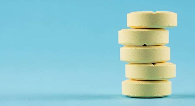Stack of yellow pills on a light blue background studio shot medical concept