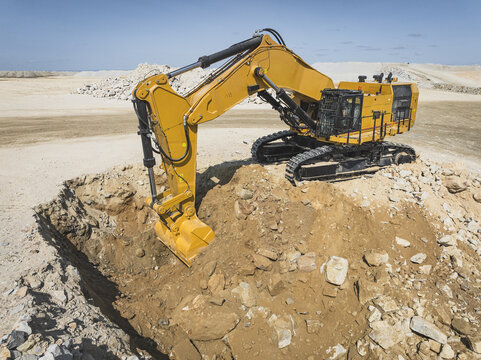 Santa Lucia de Gordon, Spain: View of a large yellow excavator parked in a quarry under a clear blue sky.